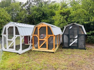 Three barn coops side by side: white, natural stained and black