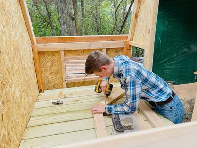 Screwing down the treated plank floor inside a henhouse