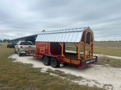 A red barn coop on a trailer arriving at a home in the country