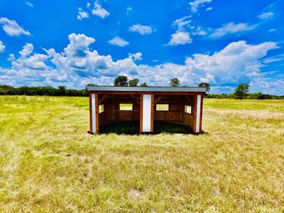 Loafing shed standing in an open pasture under a blue sky