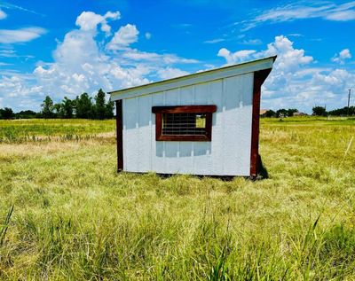 Side of a loafing shed with reddish-brown trim and a cattle-panel window