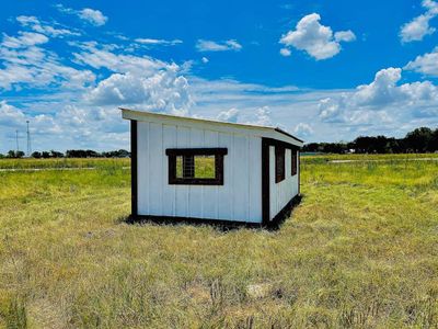 Back corner of a white loafing shed with dark trim and a roof sloping to the back