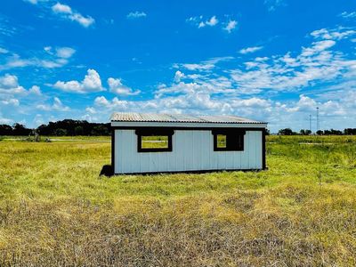 Back wall of a white loafing shed with two cattle-panel windows in dark frames