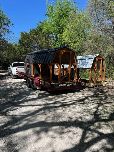 A black and natural barn coop on the Harmony Coops trailer behind a white pickup